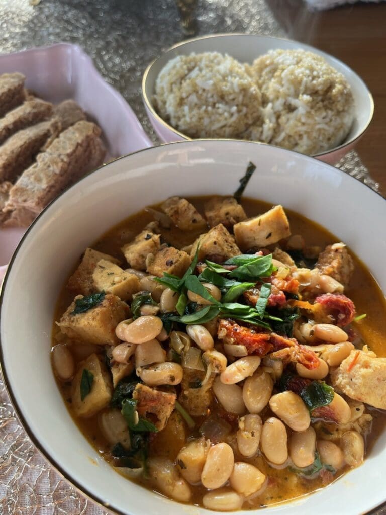 A bowl of food on the table next to some bread.