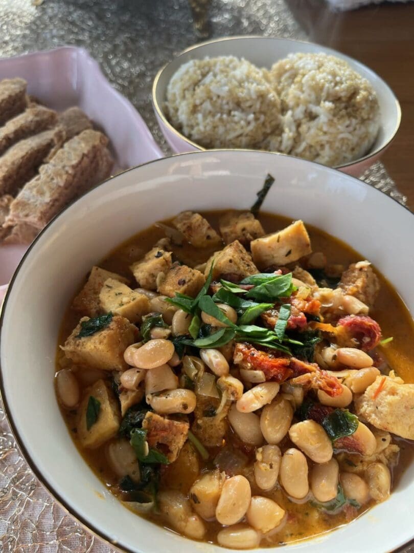 A bowl of food on the table next to some bread.