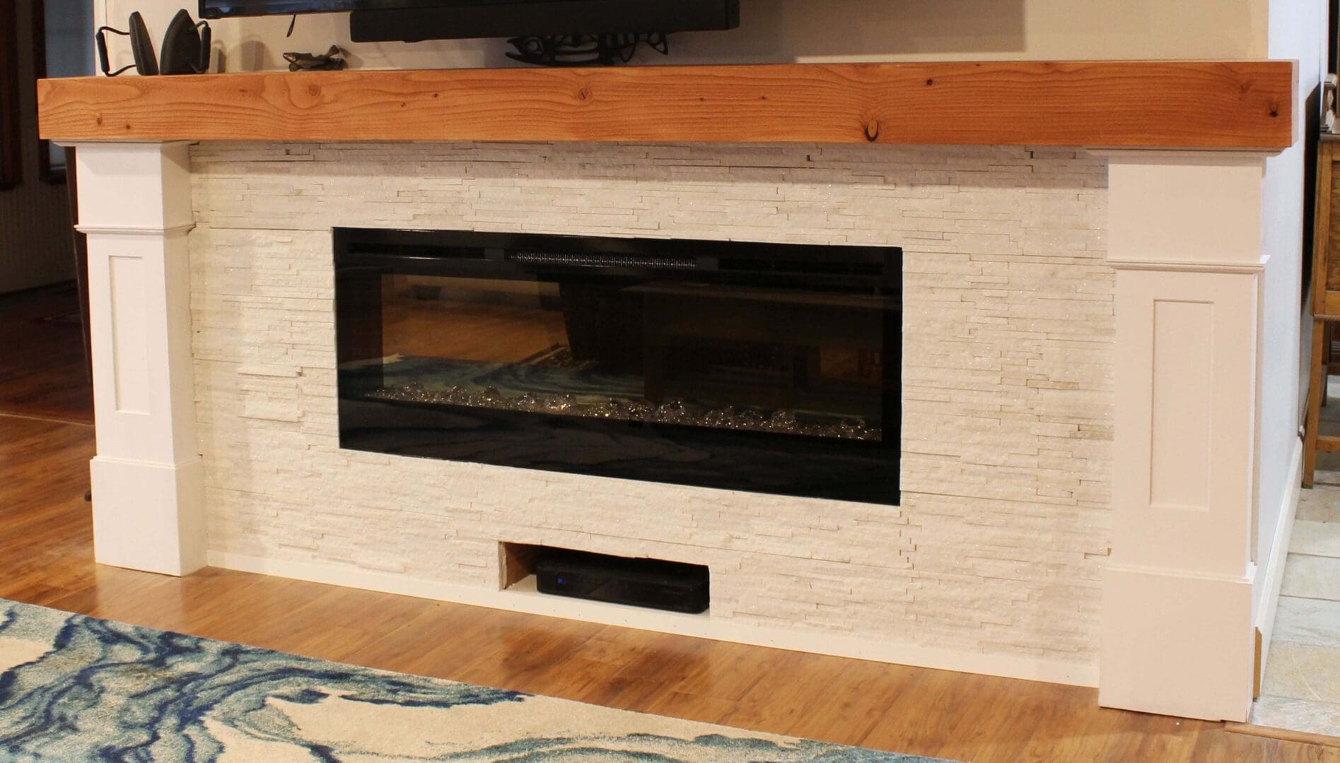 A fireplace with a wooden mantle and white brick.