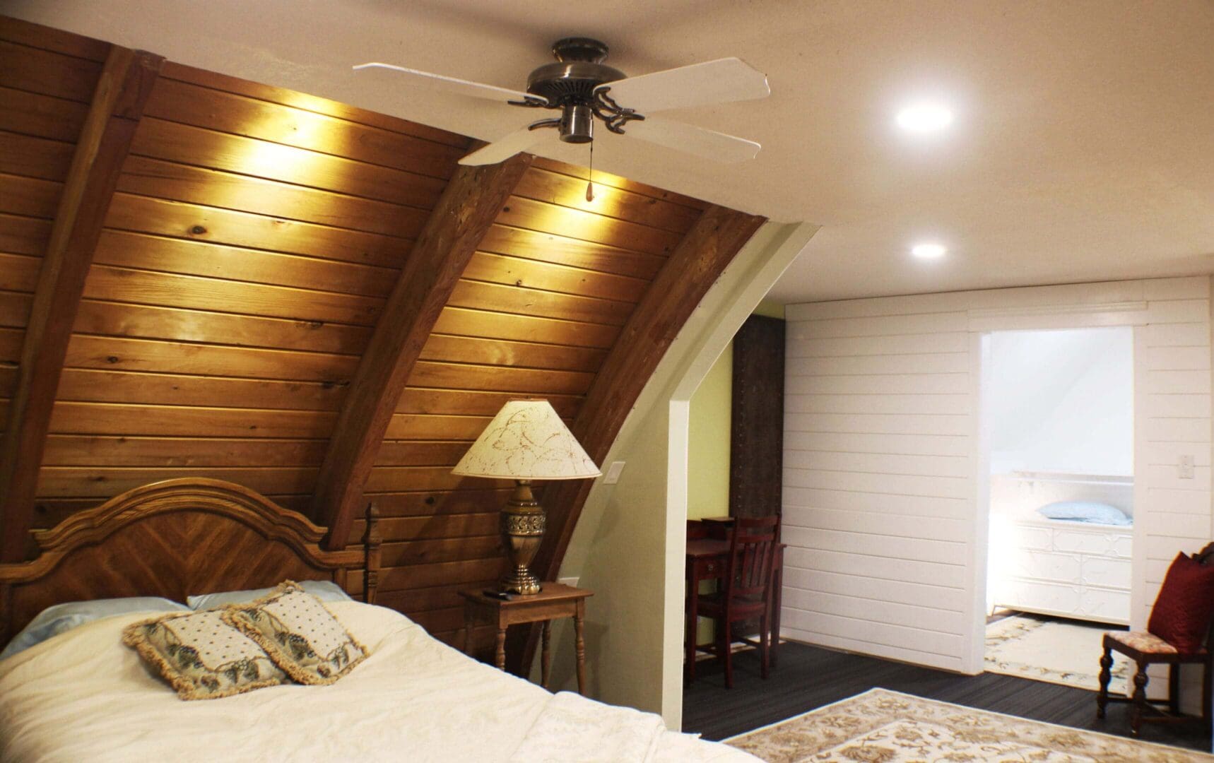 A bedroom with a bed, ceiling fan and lamps.