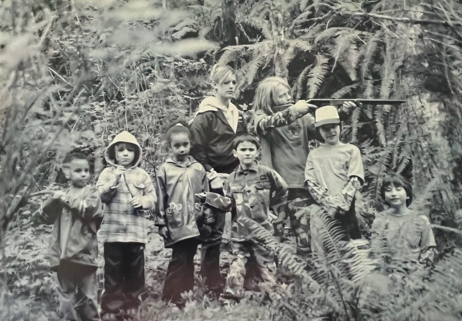 A group of children standing in the woods with guns.
