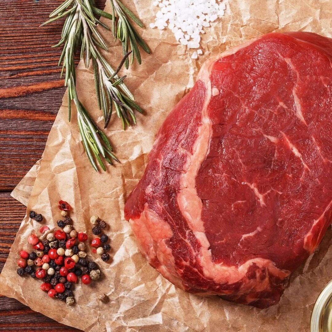 A piece of meat sitting on top of paper next to spices.
